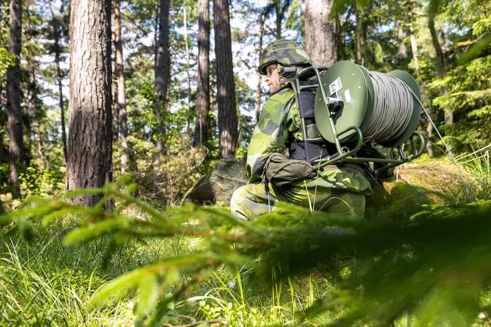 Soldier deploying tactical fiber cable in a forest